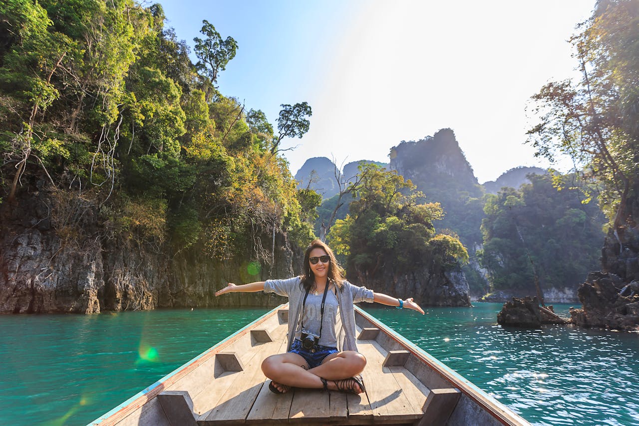 menu-05 Asian woman relishing a serene boat journey through the lush karst landscape of Thailand's Khlong Sok.