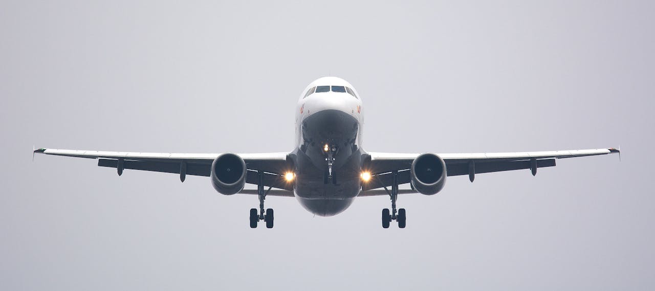 menu-02 A commercial airliner captured head-on, preparing to land against a cloudy sky.